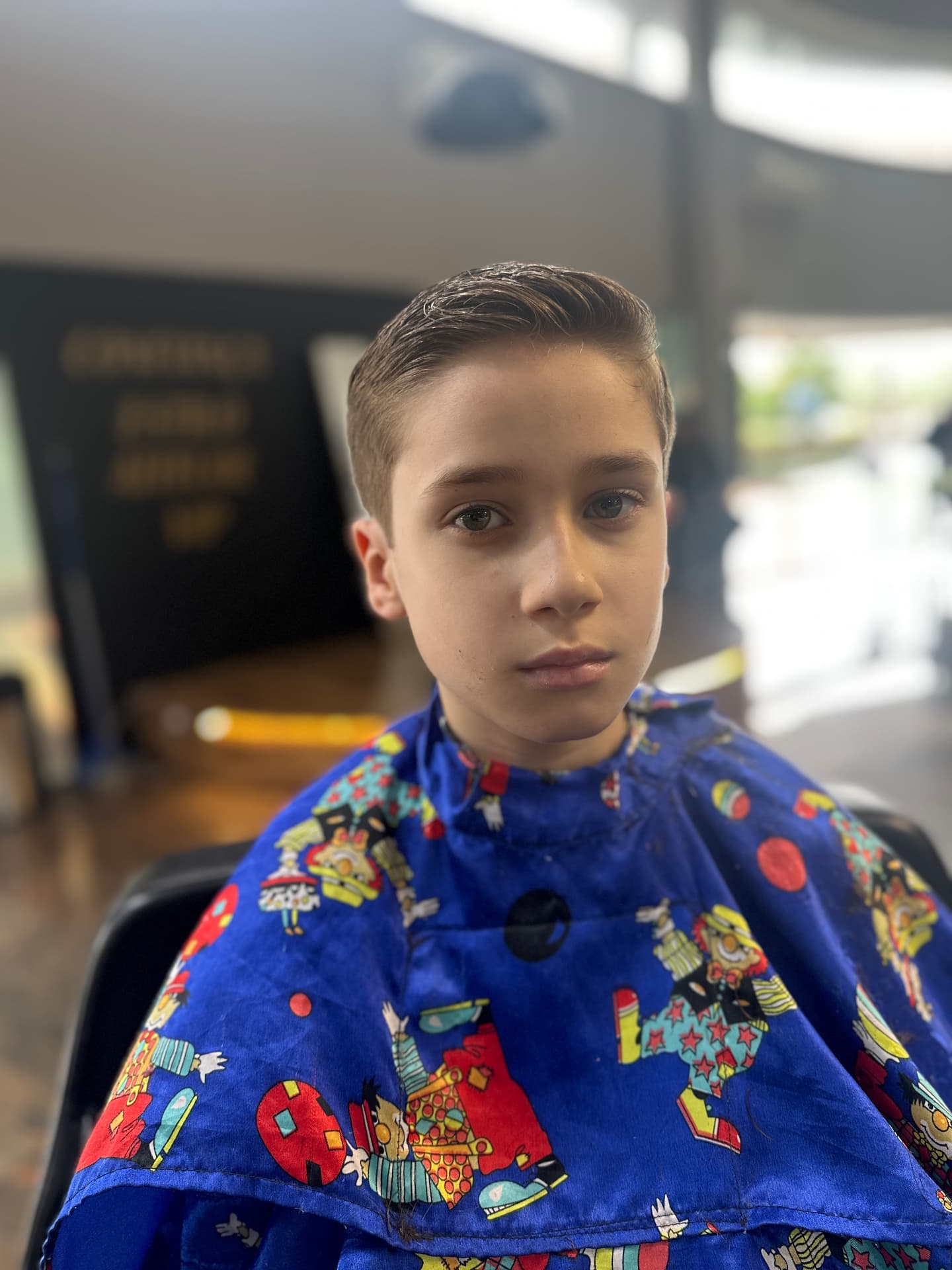 Corte infantil social com topo penteado para trás, visto de frente
