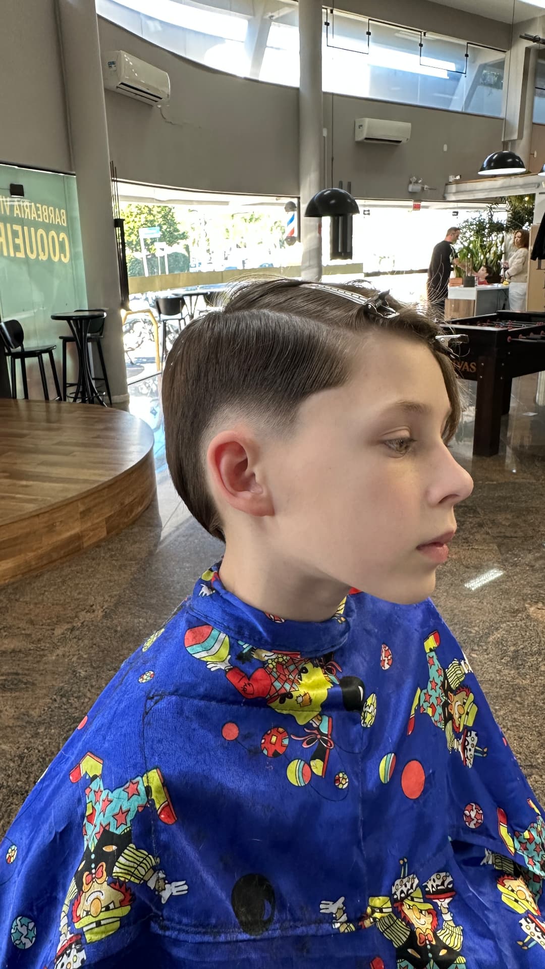 Corte infantil em andamento, cabelo penteado para trás, visto de perfil